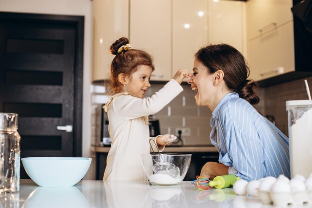 Mãe com filha se divertindo com farinha na cozinha