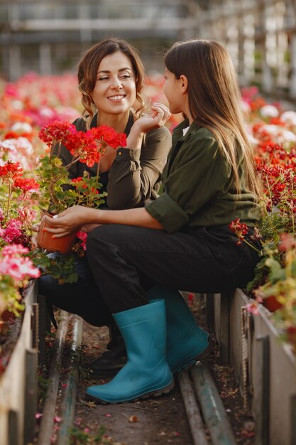 Mãe com filha. Trabalhadores com potes de flores. Menina em uma camisa verde