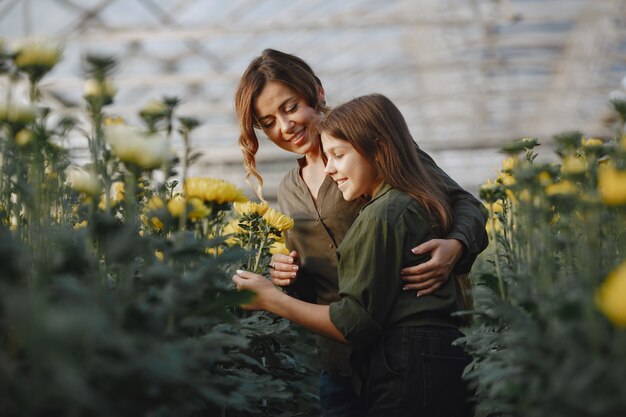 Mãe com filha. Trabalhadores com potes de flores. Menina em uma camisa verde