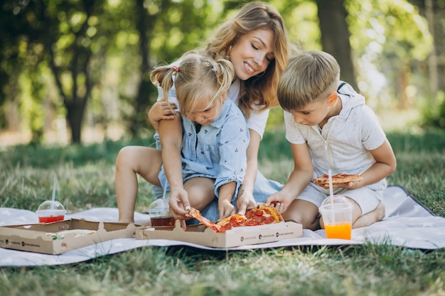 Mãe com filho e filha comendo pizza no parque