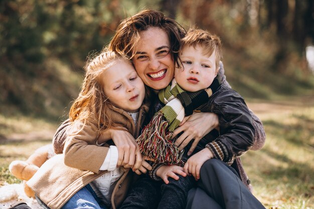 Mãe com filhos fazendo piquenique na floresta