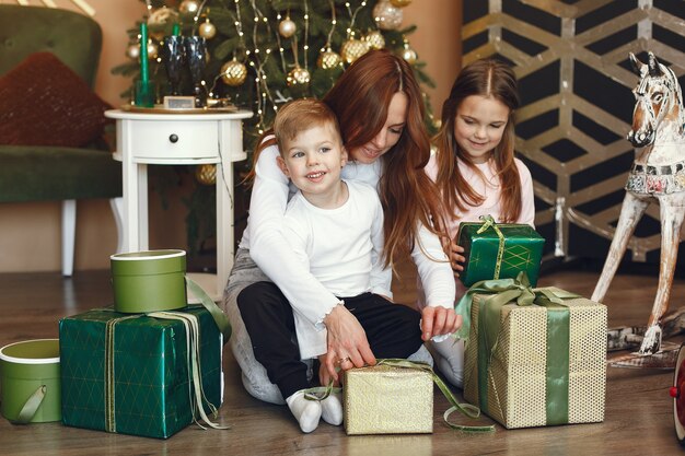 Mãe com filhos fofos perto da árvore de natal