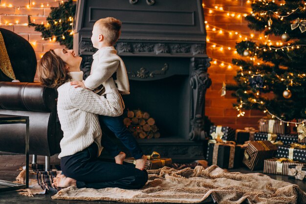 Mãe com seu filho pequeno sentado perto da árvore de Natal