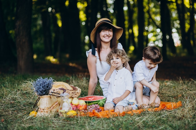 Mãe com seus filhos fazendo piquenique na floresta