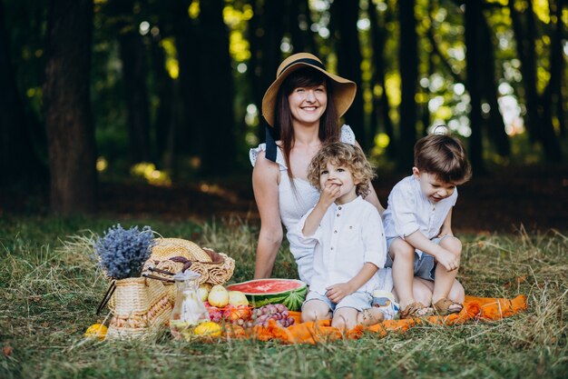 Mãe com seus filhos fazendo piquenique na floresta