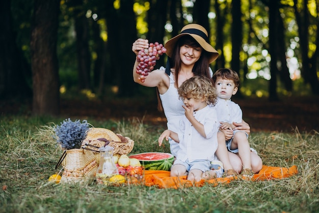 Mãe com seus filhos fazendo piquenique na floresta