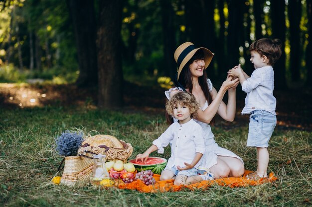 Mãe com seus filhos fazendo piquenique na floresta