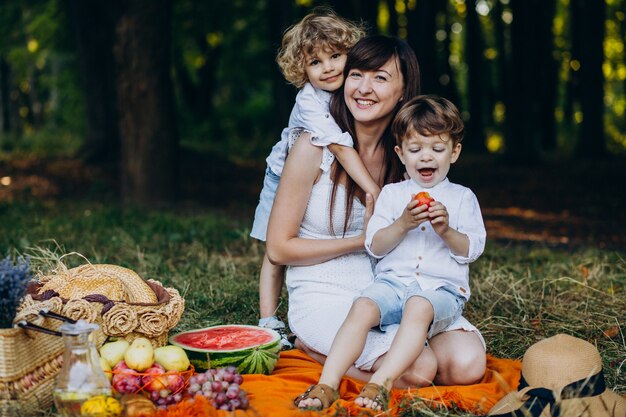 Mãe com seus filhos fazendo piquenique na floresta