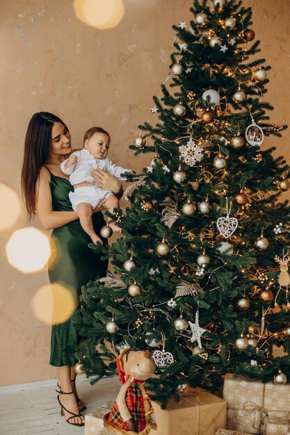 Mãe com sua filha bebê perto da árvore de natal