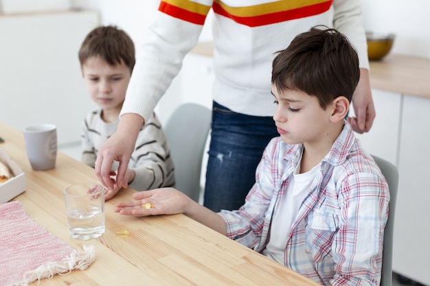 Mãe dando vitaminas às crianças para protegê-las do vírus