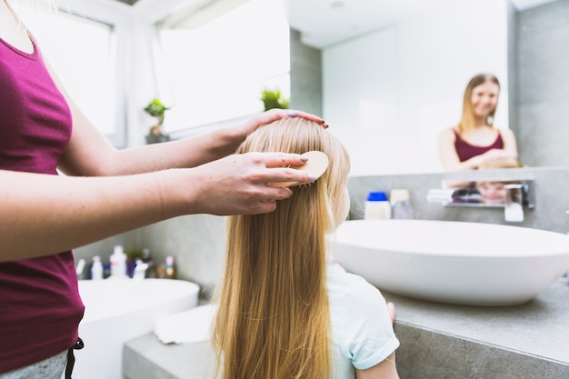 Mãe de colheita escovar o cabelo da filha