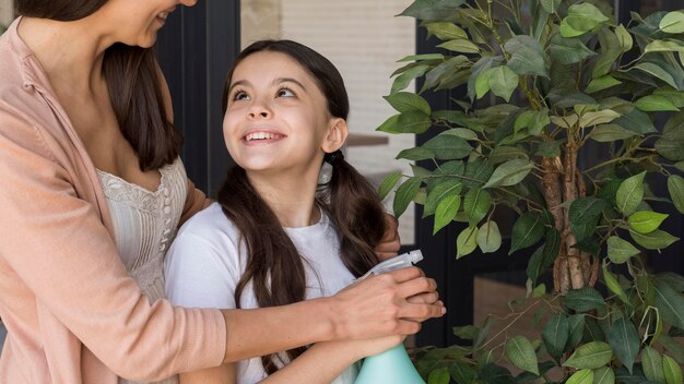 Mãe de Cose-up e planta molhando da menina