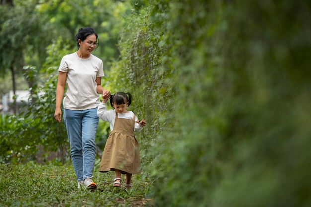 Mãe de tiro completo e menina caminhando na natureza