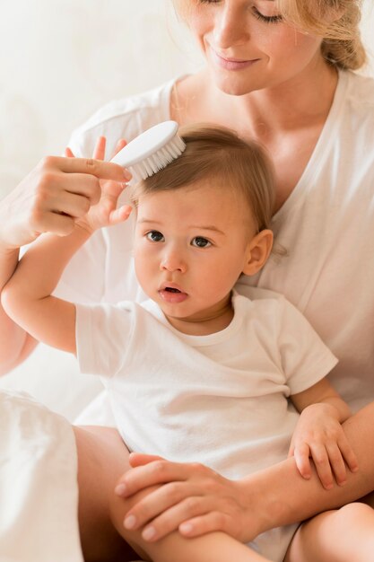 Mãe de tiro médio escovar o cabelo do bebê