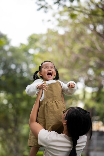 Mãe de tiro médio segurando menina ao ar livre