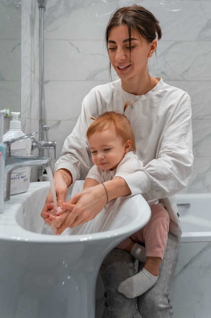 Mãe de vista frontal lavando bebê