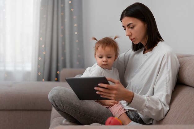 Foto grátis mãe de vista lateral com tablet e bebê