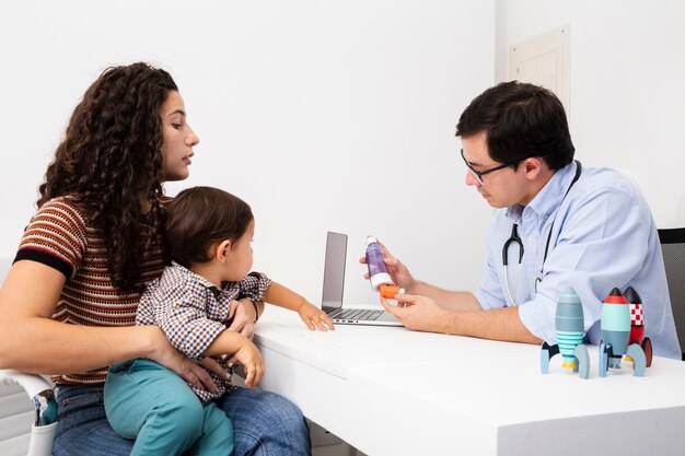 Mãe de vista lateral prestando atenção na visita de um médico