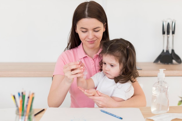 Mãe despejando desinfetante para menina