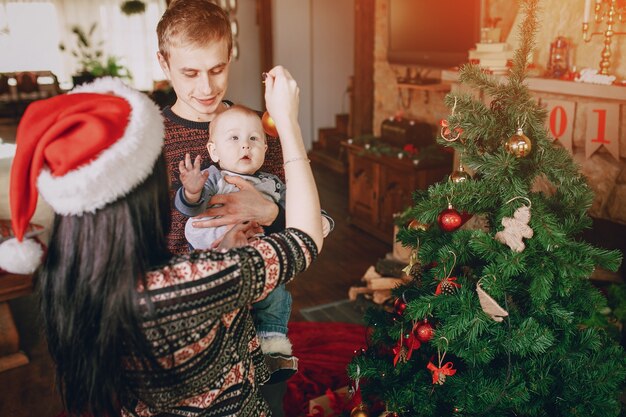 Mãe distrair o bebê com um enfeite de natal enquanto o pai prende-lo em seus braços