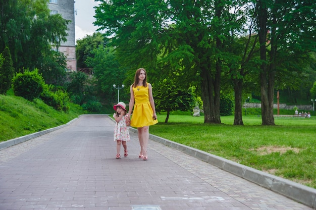 Mãe e filha andando em uma estrada asfaltada