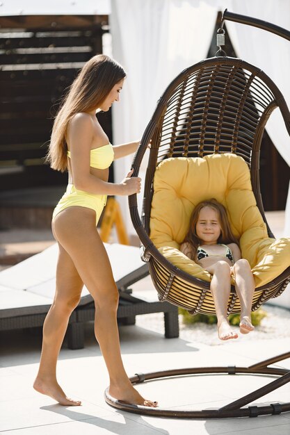 Mãe e filha aproveitando as férias de verão. Menina em uma cadeira, mãe tirando fotos.