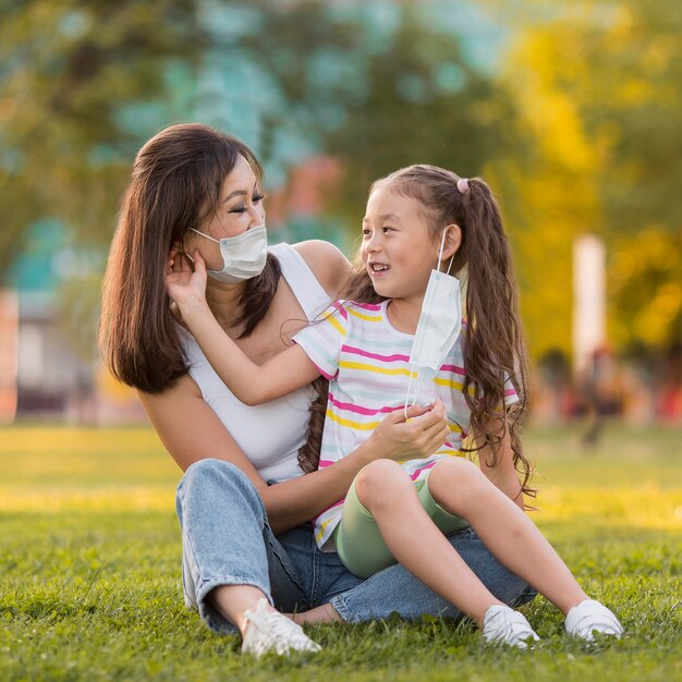 Mãe e filha asiáticas com máscaras médicas