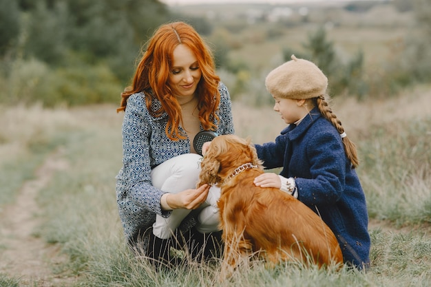 Mãe e filha brincando com o cachorro. família no parque outono. animal de estimação, animal doméstico e conceito de estilo de vida. tempo de outono.