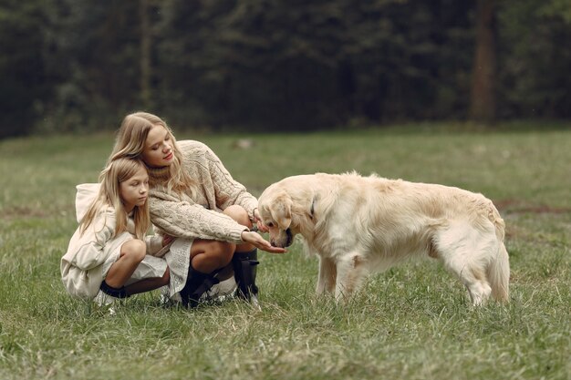 Mãe e filha brincando com o cachorro. Família no parque outono. Animal de estimação, animal doméstico e conceito de estilo de vida