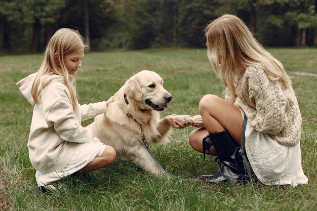 Mãe e filha brincando com o cachorro. Família no parque outono. Animal de estimação, animal doméstico e conceito de estilo de vida