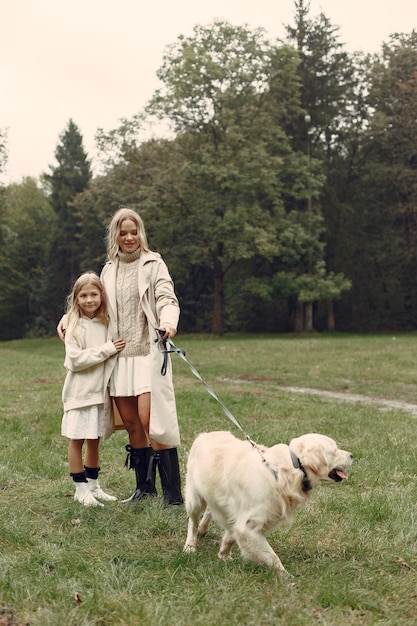 Mãe e filha brincando com o cachorro. Família no parque outono. Animal de estimação, animal doméstico e conceito de estilo de vida