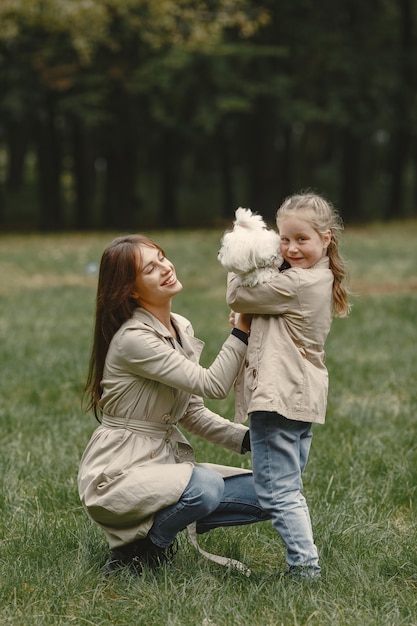 Mãe e filha brincando com o cachorro. Família no parque outono. Animal de estimação, animal doméstico e conceito de estilo de vida