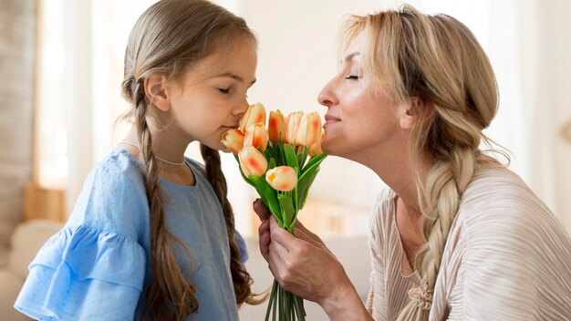 Mãe e filha cheirando buquê de tulipas