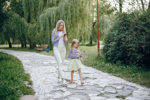 Mãe e filha com um celular e um tablet caminhando em um parque