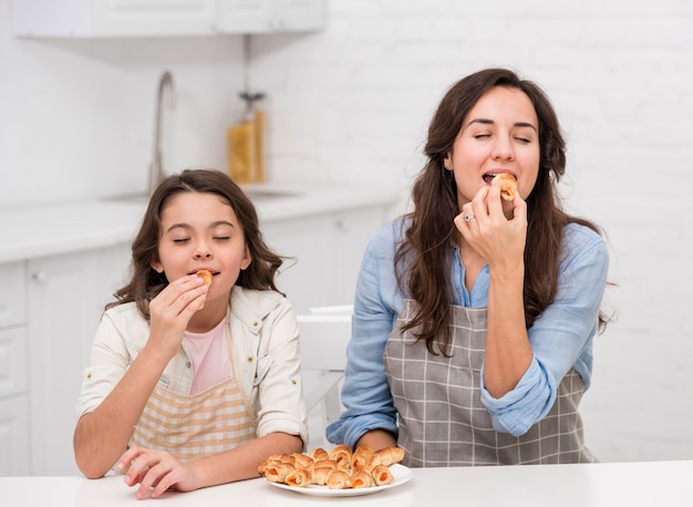 Mãe e filha comendo alguns bolos juntos