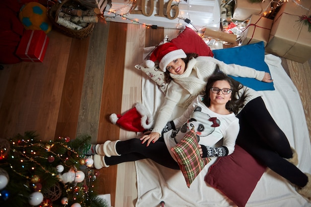 Mãe e filha, deitado no chão juntos em casa no Natal