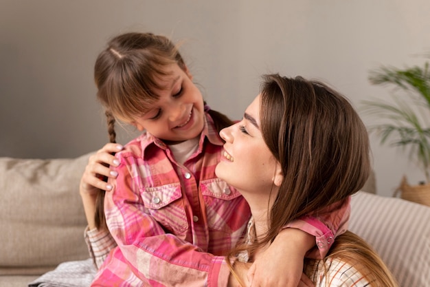 Foto grátis mãe e filha em casa se abraçando