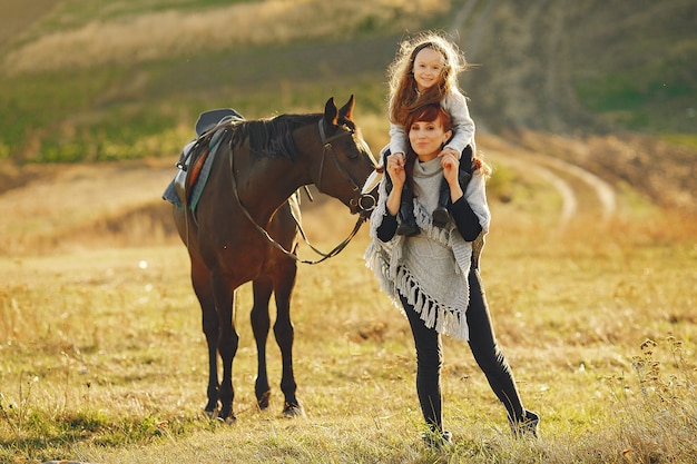 Mãe e filha em um campo brincando com um cavalo