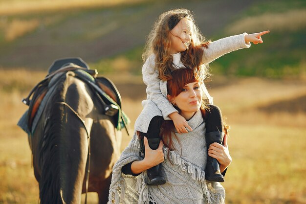 Mãe e filha em um campo brincando com um cavalo