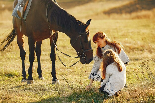 Mãe e filha em um campo brincando com um cavalo