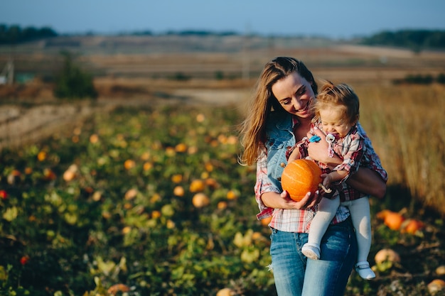 Mãe e filha em um campo com abóboras, véspera de halloween