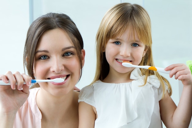 Mãe e filha escovando dentes no banheiro