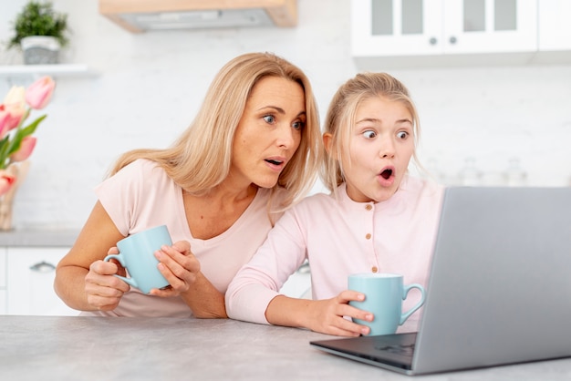 Mãe e filha espantadas olhando no laptop