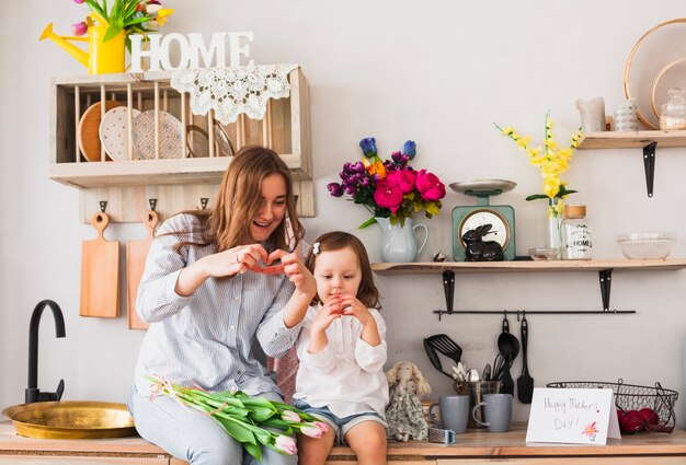 Mãe e filha fazendo formato de coração com as mãos