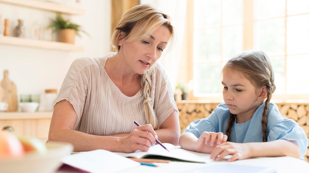 Mãe e filha fazendo lição de casa em casa