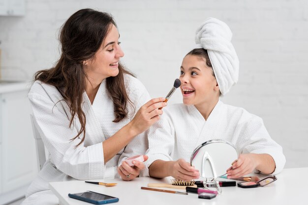 Mãe e filha fazendo sua maquiagem juntos