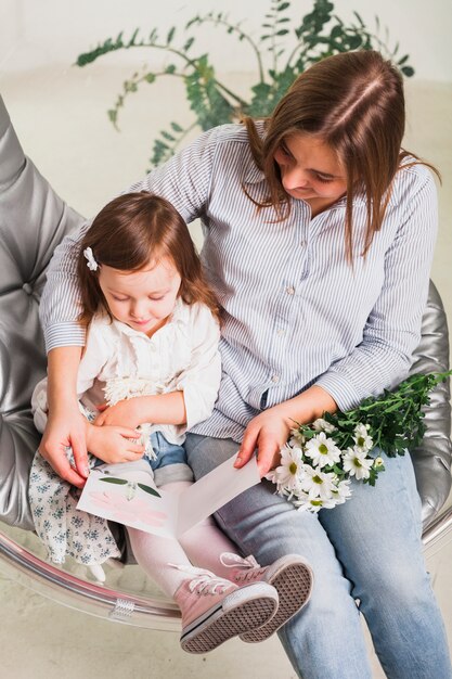 Mãe e filha lendo cartão