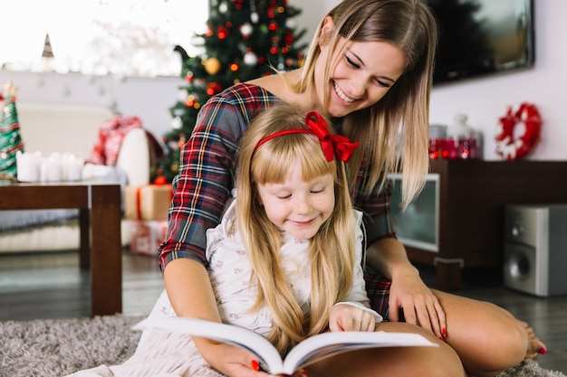 Foto grátis mãe e filha lendo na sala de estar