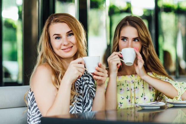 Mãe e filha loira conversam e sorriem enquanto bebem café com leite