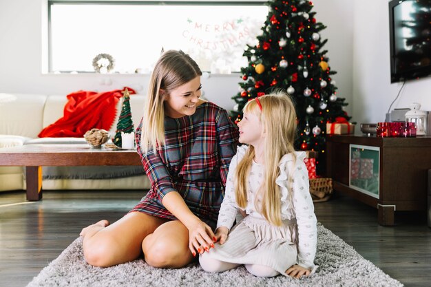 Mãe e filha na sala de estar com árvore de natal